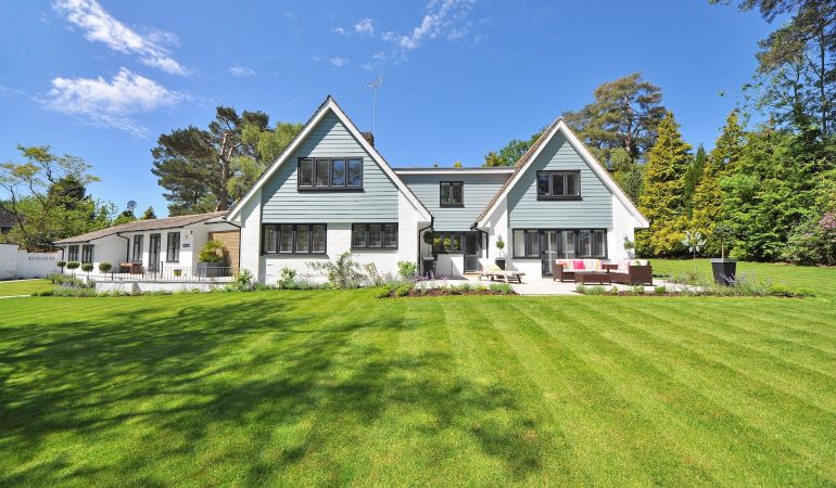white and gray wooden house near grass field and trees
